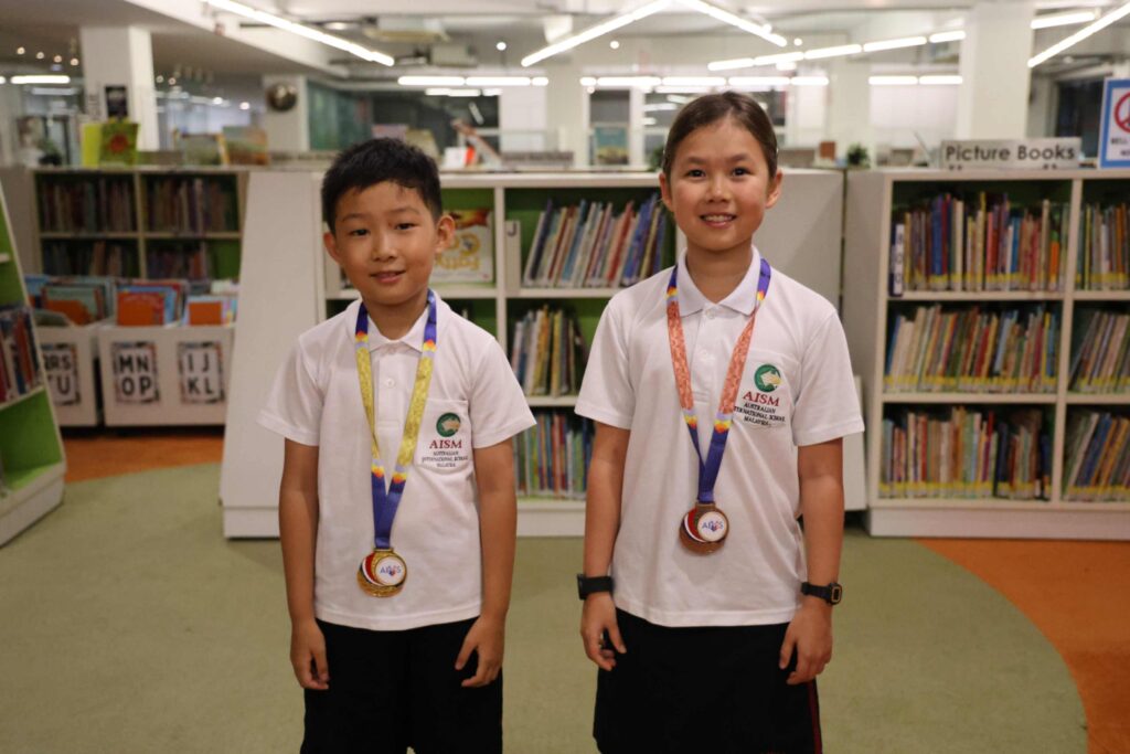 Two AISM Junior School students wearing medals after the AIMS Language Competition 2026
